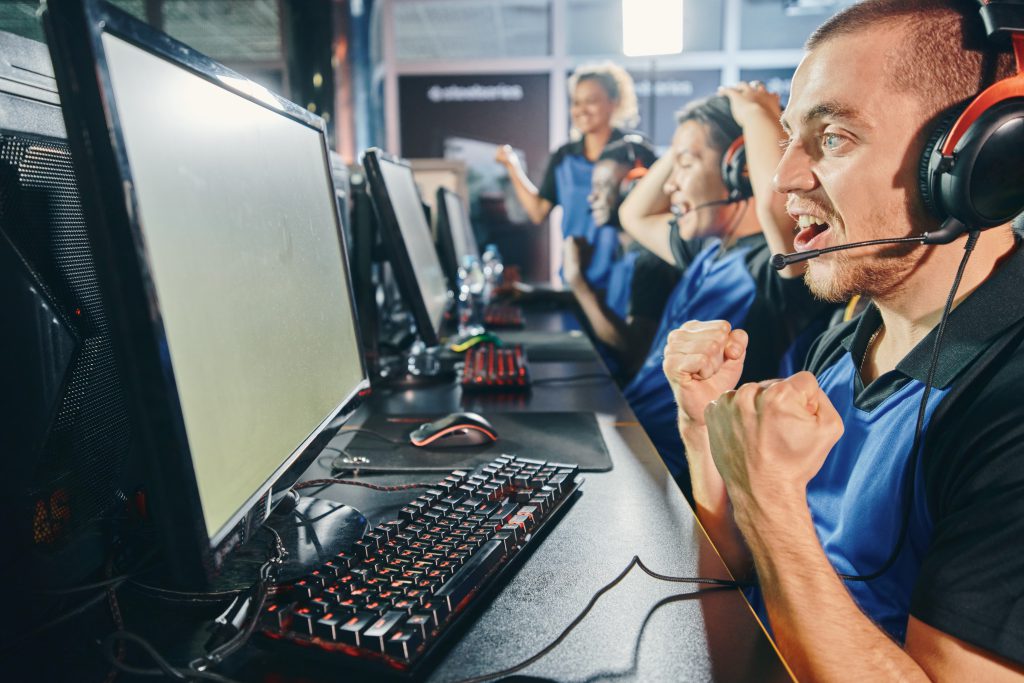 Side view of excited professional cyber gamers, multiracial cybersport team celebrating success while playing online video game, they participating in eSports tournament or competition